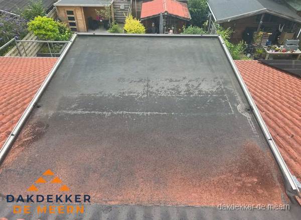 Verouderd plat dak met slijtage tussen schuine daken in De Meern Verouderd plat dak met slijtage tussen schuine daken in De Meern