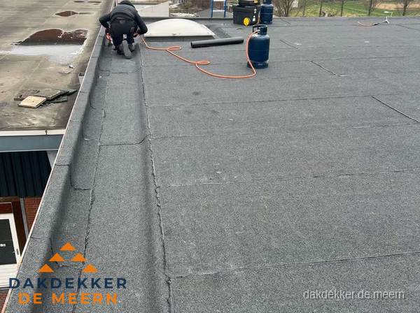 Dakdekker repareert bitumen dakbedekking op groot plat dak in De Meern Dakdekker repareert bitumen dakbedekking op groot plat dak in De Meern